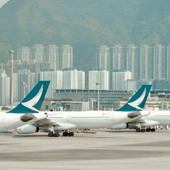 Cathay Pacific airplanes at the airport with city skyline in the background