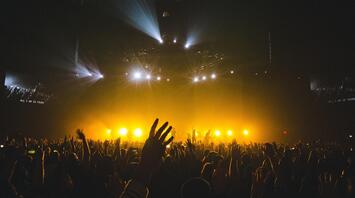 People raising hands at a concert with bright spotlights
