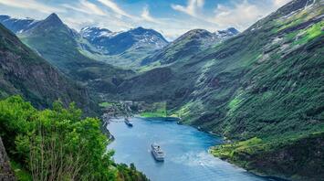 A fjord with cruise ships surrounded by tall green mountains