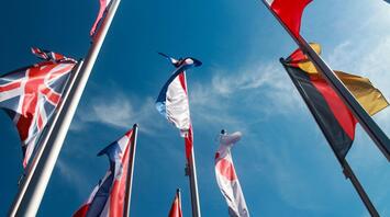 Flags of different countries against the background of a clear blue sky