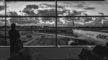 grayscale photography of man standing in front of plane