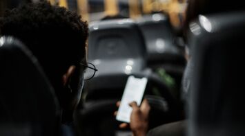 A person using a smartphone while seated on a bus with other passengers