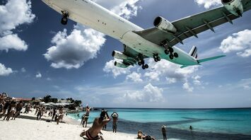 Airplane flying low over a crowded beach