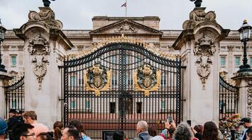 People in front of the gates of Buckingham Palace with the British flag