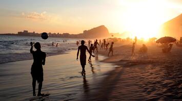 People playing beach soccer at sunset