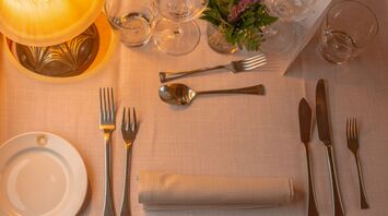 Elegant dining table set with cutlery, glassware, and a small floral arrangement