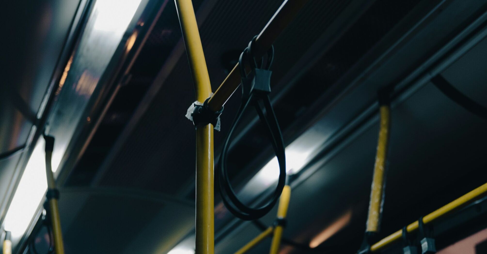 Interior of a dimly lit bus with yellow poles and hand straps