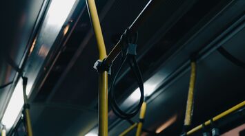 Interior of a dimly lit bus with yellow poles and hand straps