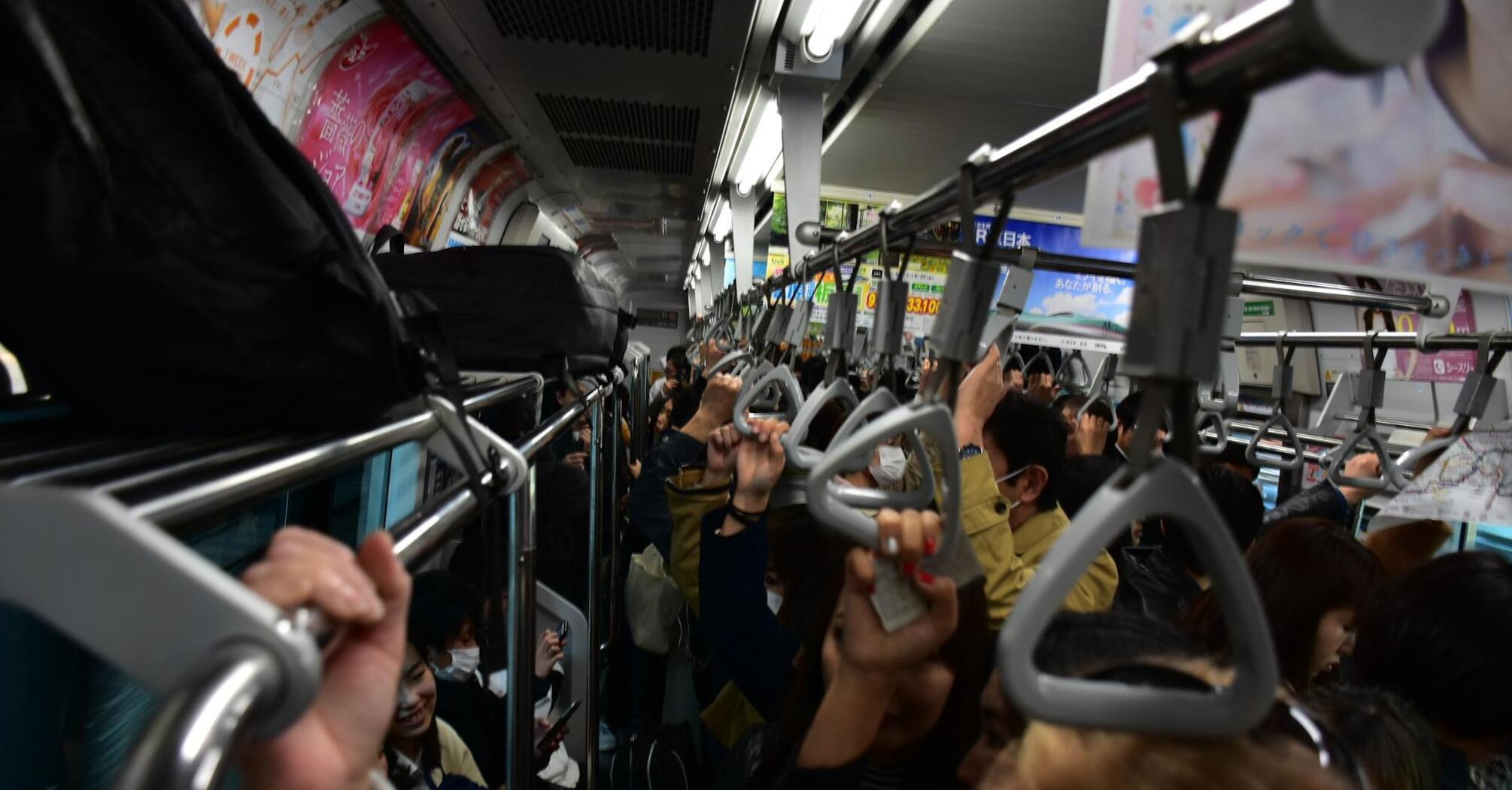 People in masks in a crowded subway holding handrails