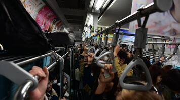 People in masks in a crowded subway holding handrails