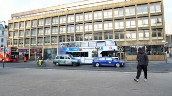 A First Glasgow bus, a cyclist, and other vehicles on a street in Glasgow with buildings in the background