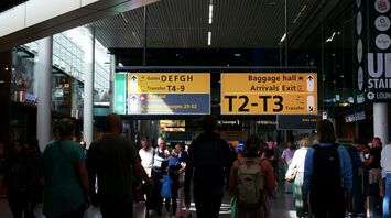 Crowded airport terminal with passengers and direction signs