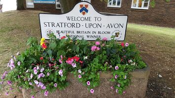 A "Welcome to Stratford-upon-Avon" sign with colorful flowers in front of the Visitor Information Centre