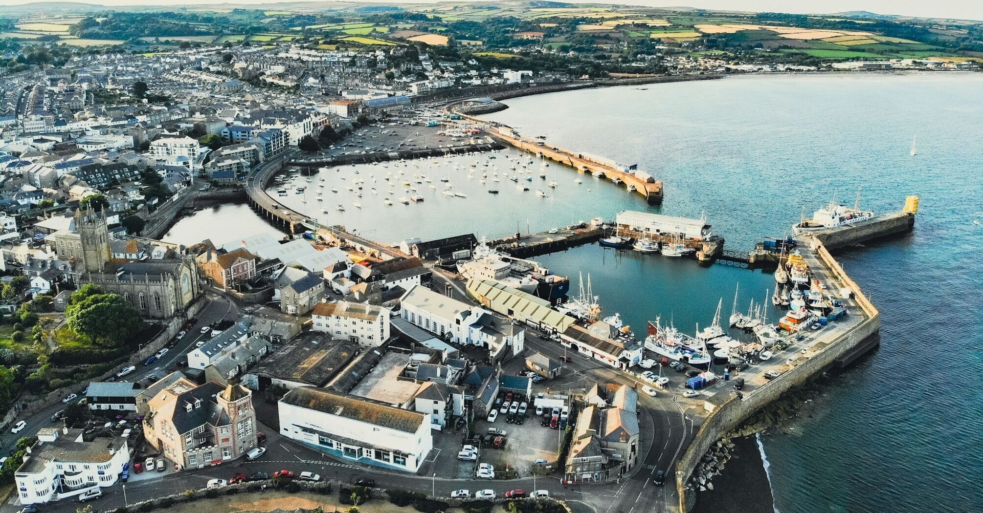 Aerial view of Penzance harbor and town, showcasing boats docked and surrounding buildings