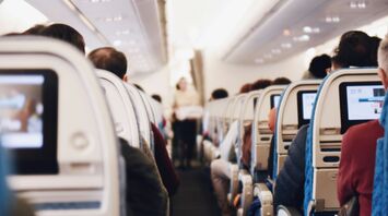 Passengers seated in an airplane cabin with in-flight entertainment screens