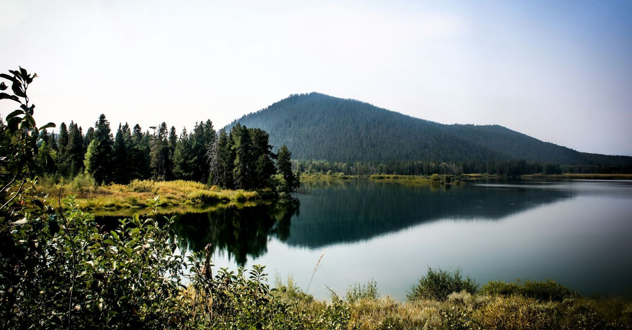 A serene lake surrounded by trees with a mountain in the background