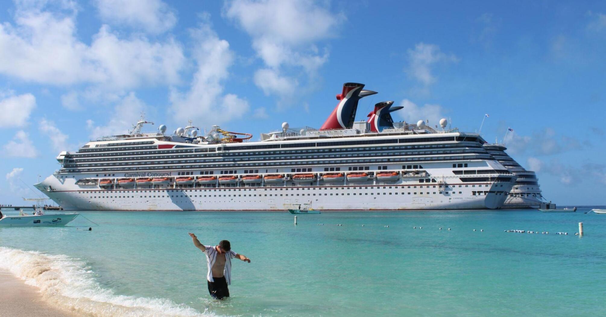 Man on the beach in front of a cruise ship at sea