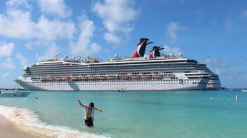 Man on the beach in front of a cruise ship at sea