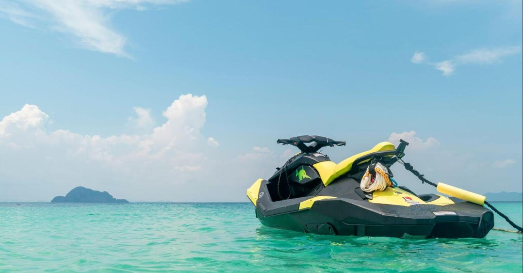 Yellow jet ski on clear water with an island in the distance