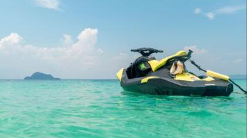 Yellow jet ski on clear water with an island in the distance
