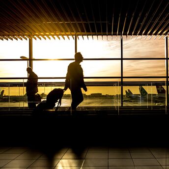 Passengers walking at the airport terminal with a sunrise in the background
