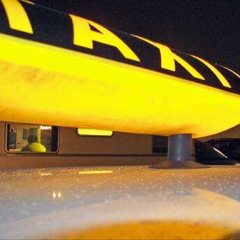 Yellow taxi sign with a Ferris wheel in the background