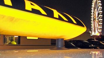 Yellow taxi sign with a Ferris wheel in the background