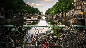 assorted color bicycles park beside blue rails near river
