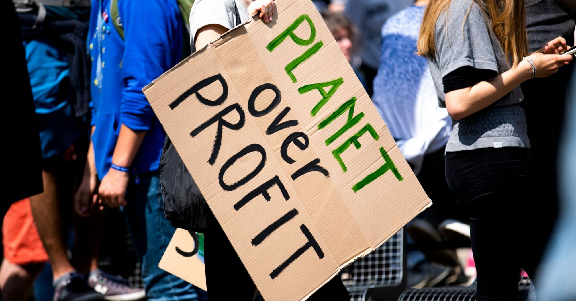 woman holding planet over profit placard