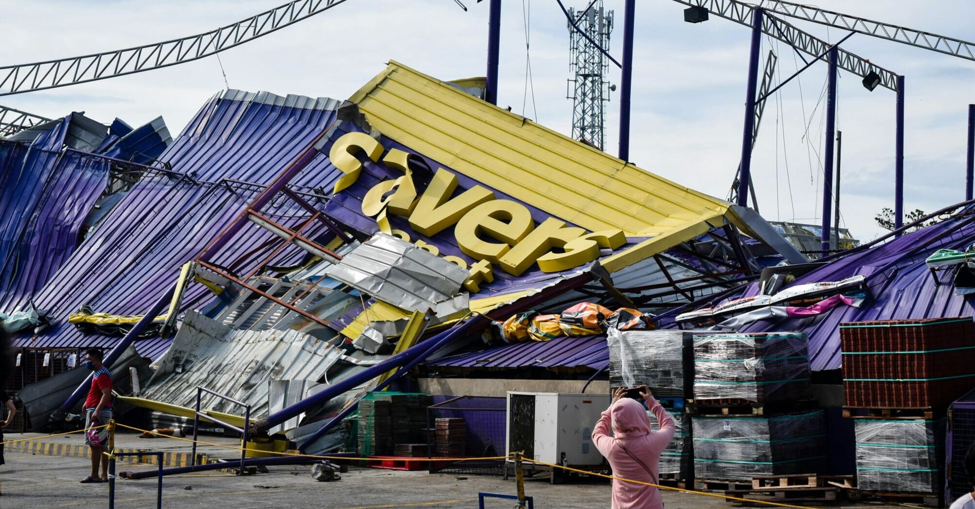 a woman standing in front of a building that has been blown over