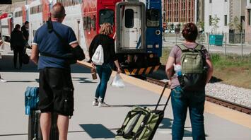 Passengers with luggage wait for the train at the station