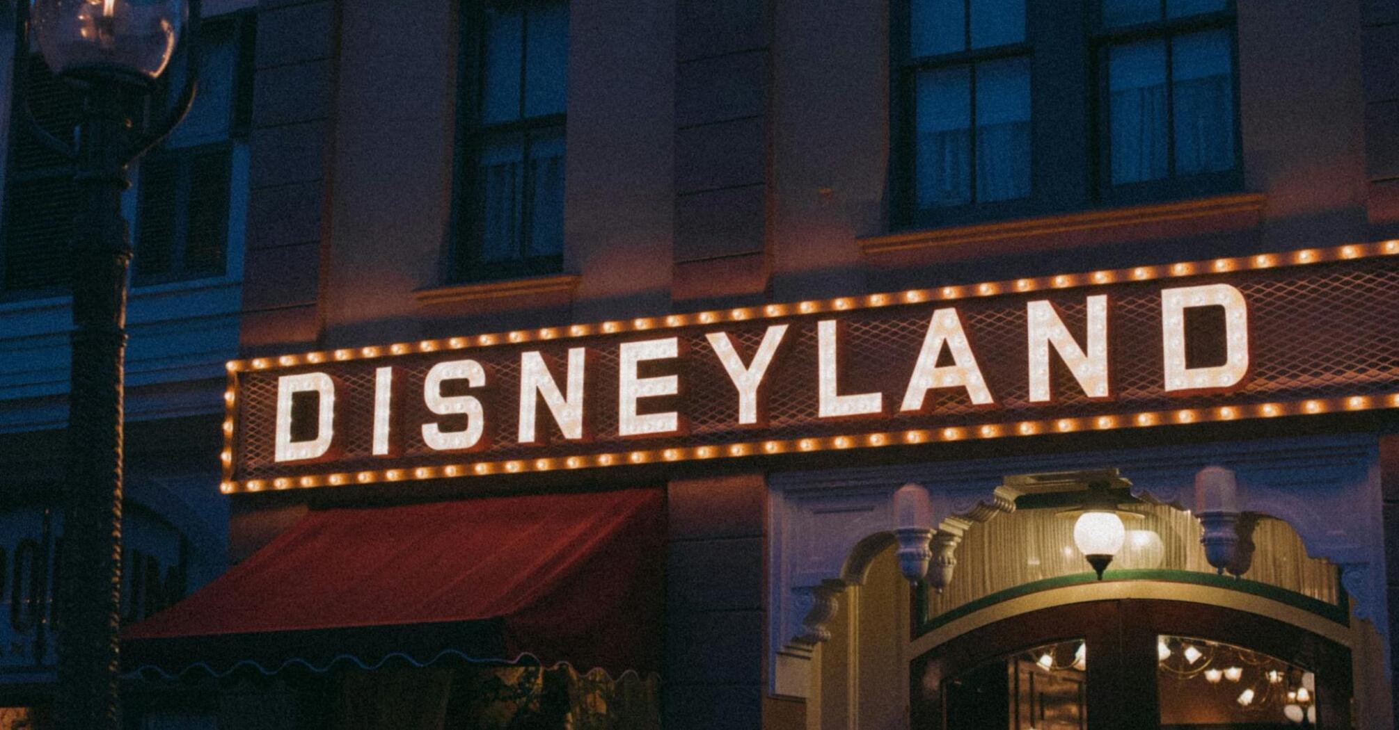 Disneyland sign at night with lighting and display cases