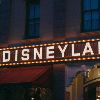 Disneyland sign at night with lighting and display cases