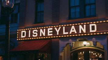 Disneyland sign at night with lighting and display cases