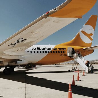 FlyBondi Boeing 737-800 on the tarmac with boarding stairs and safety cones