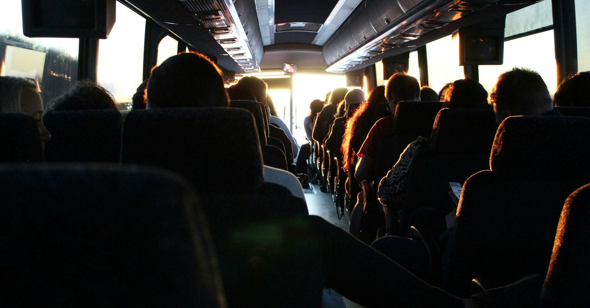 Passengers seated inside a bus, traveling during sunset