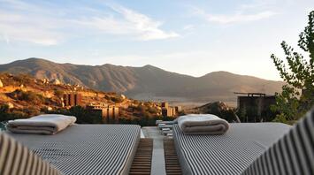 Two sun loungers with blankets against a background of mountains and sky