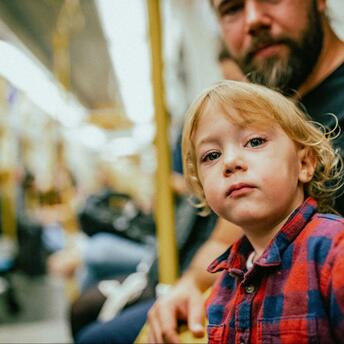 A boy with his father in the subway, sitting on a bench