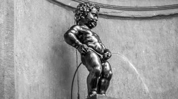 A bronze statue of a little boy urinating