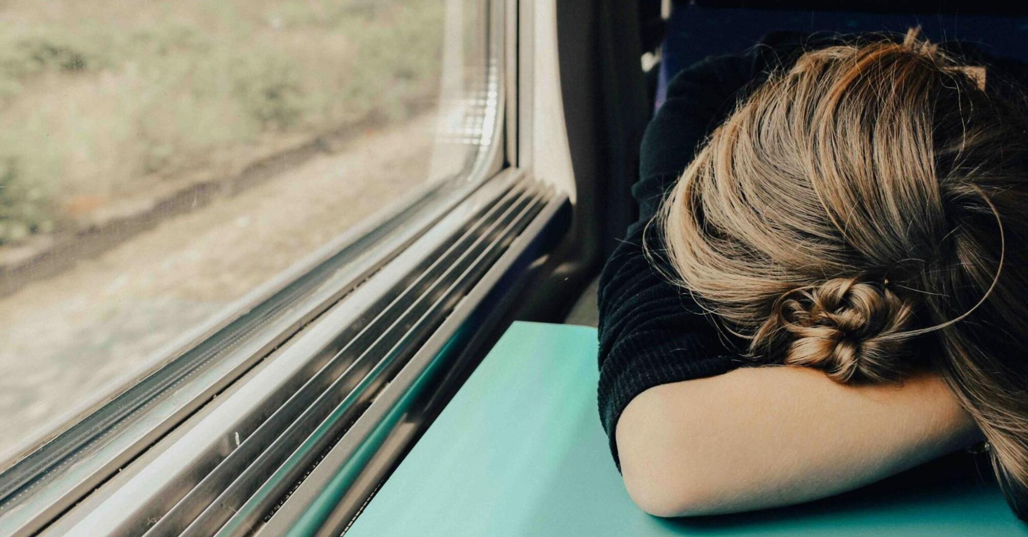 A person resting their head on a table in transport