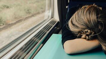 A person resting their head on a table in transport