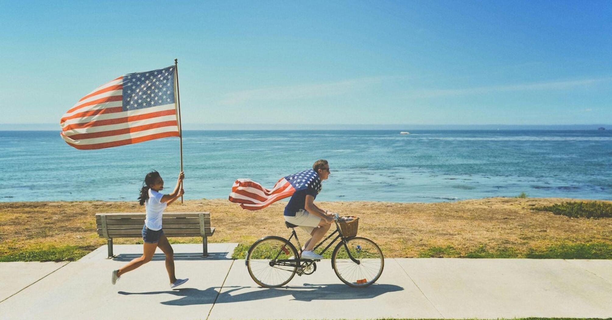 People with US flags celebrating Independence Day on the seashore