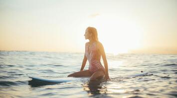 Woman surfing in the ocean on the sunset