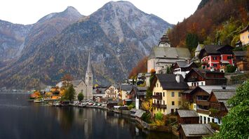 Scenic view of a lakeside village with traditional European architecture and mountainous background