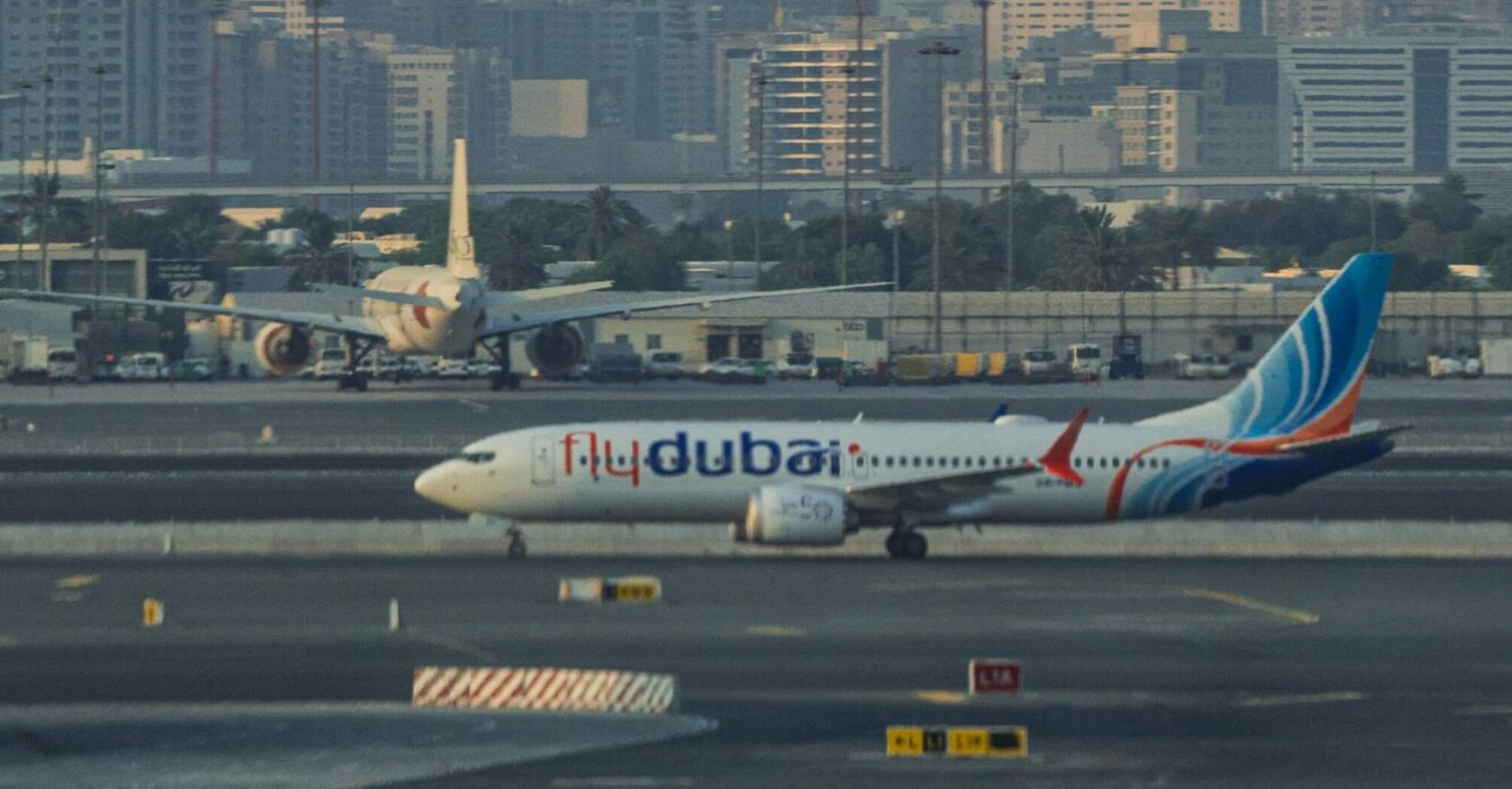 Flydubai airplane on runway with city skyline in the background