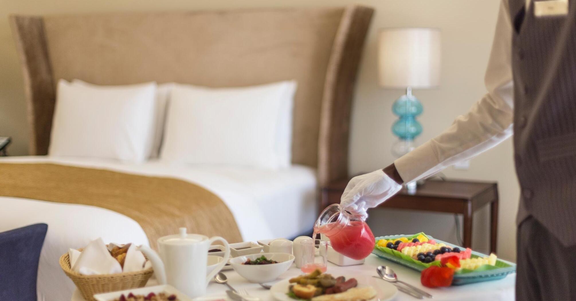 Person serving breakfast on a tray in a hotel room