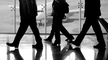 Business travelers walking through an airport with an airplane in the background