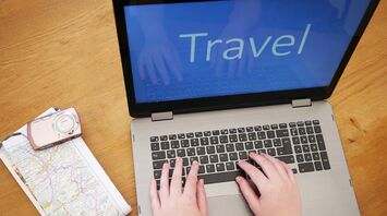 Person booking travel online with laptop