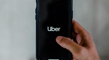 Man holding smartphone with Uber app open on screen