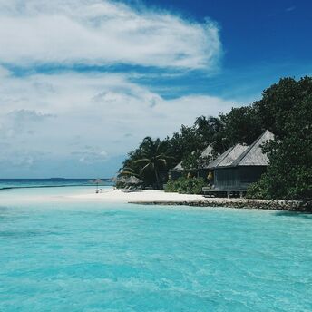 Beautiful beach in the Maldives with clear blue water and tropical huts